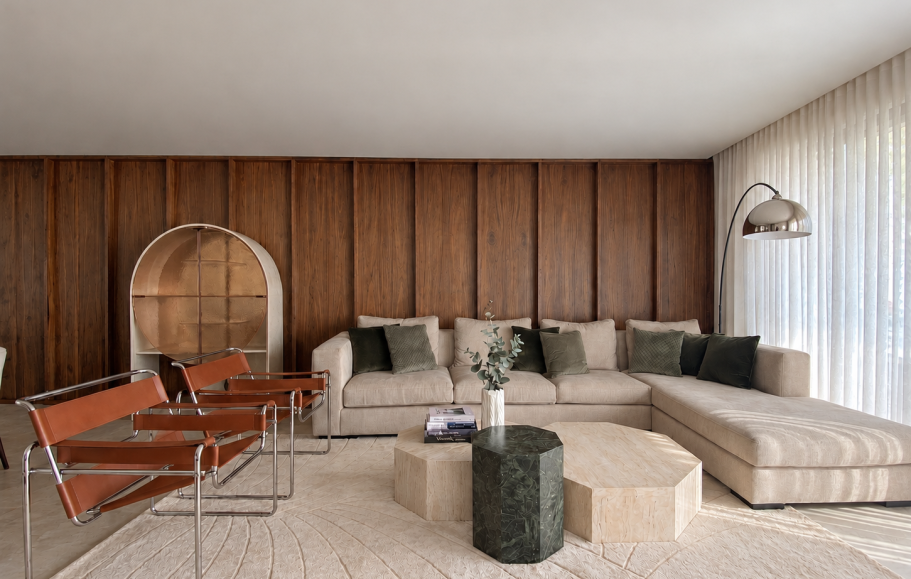 INTERIORISMO FUENGIROLA Salón moderno con sillas de madera, mesa de centro y estantería, con luz natural abundante.