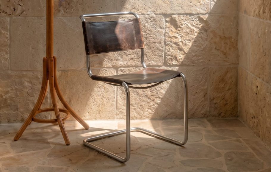 INTERIORISMO FUENGIROLA Salón moderno con sillas de madera, mesa de centro y estantería, con luz natural abundante.