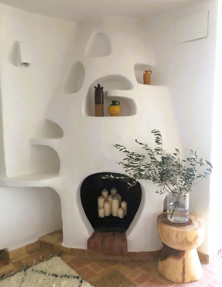 INTERIORISMO FUENGIROLA Salón moderno con sillas de madera, mesa de centro y estantería, con luz natural abundante.